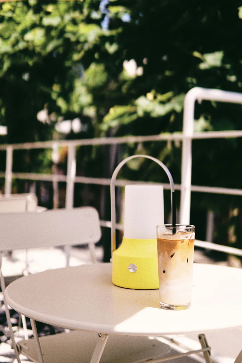 An iced coffee in a tall glass on an outdoor café table.