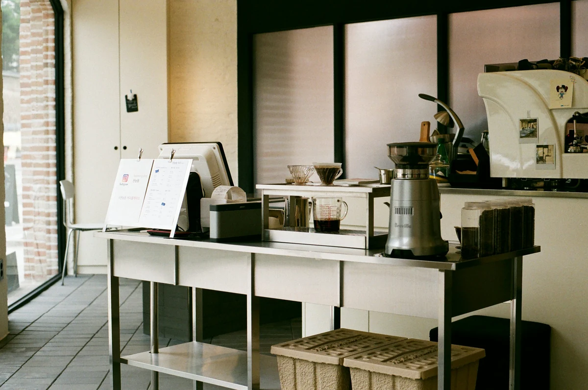 A café counter with a standing menu, register, receipt printer and coffee equipment.