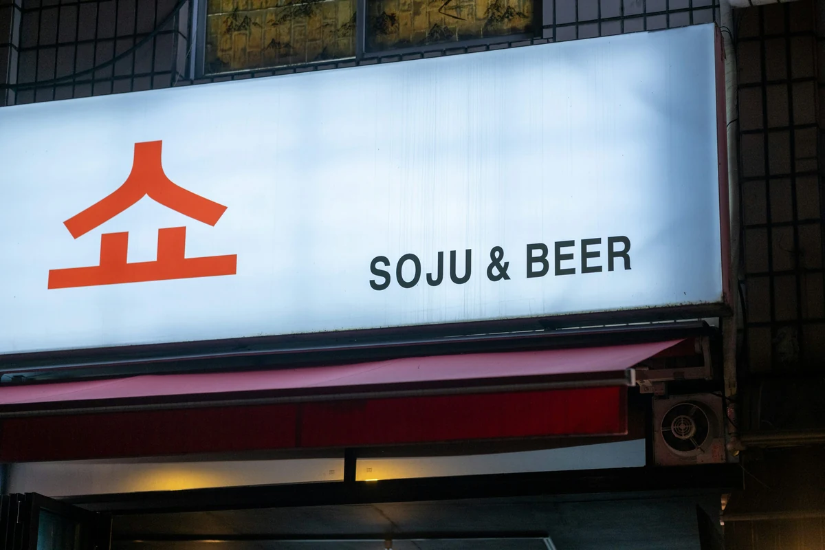 An illuminated storefront sign reading SOJU & BEER.