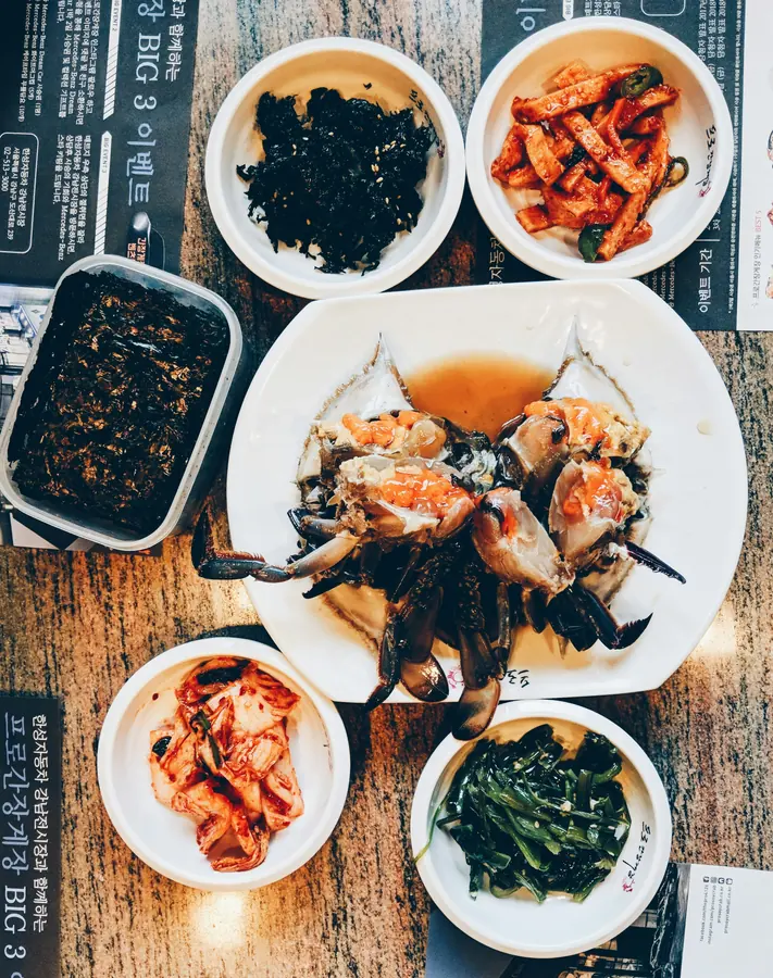 Crab on a restaurant table, surrounded by seaweed, kimchi and other side dishes.