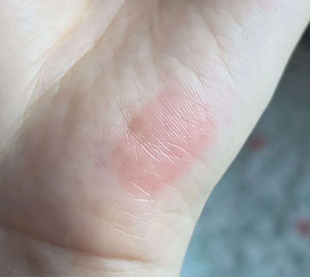 A light pink-coral swatch of Honey Dew Melon 27 on the inner wrist, with skin texture visible.