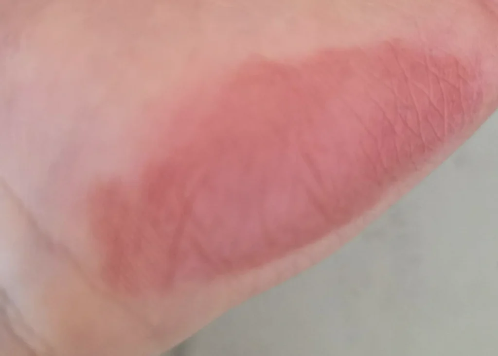 Close-up of a pink-toned lip-tint swatch across the lower palm.