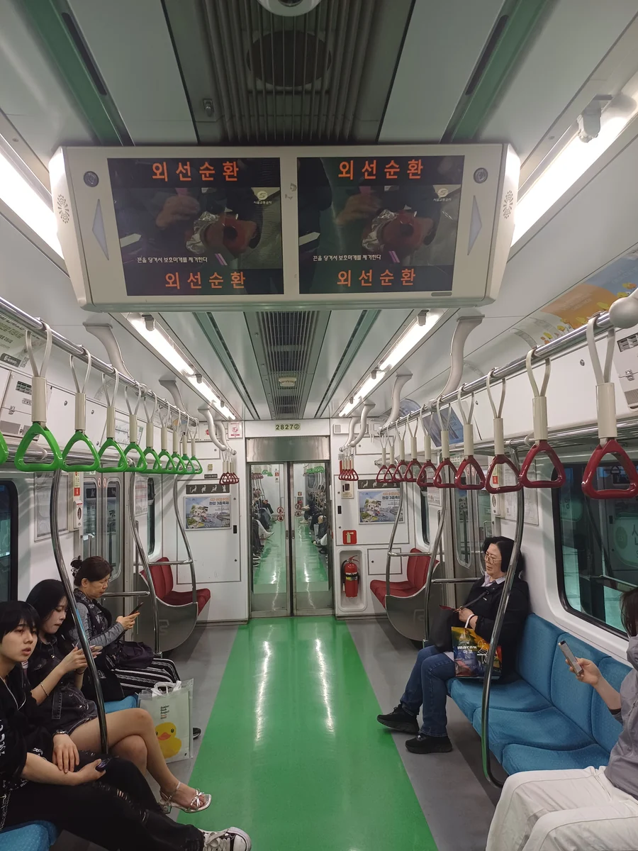 Red priority seats and priority-user pictograms at the end of a Seoul Line 2 carriage.