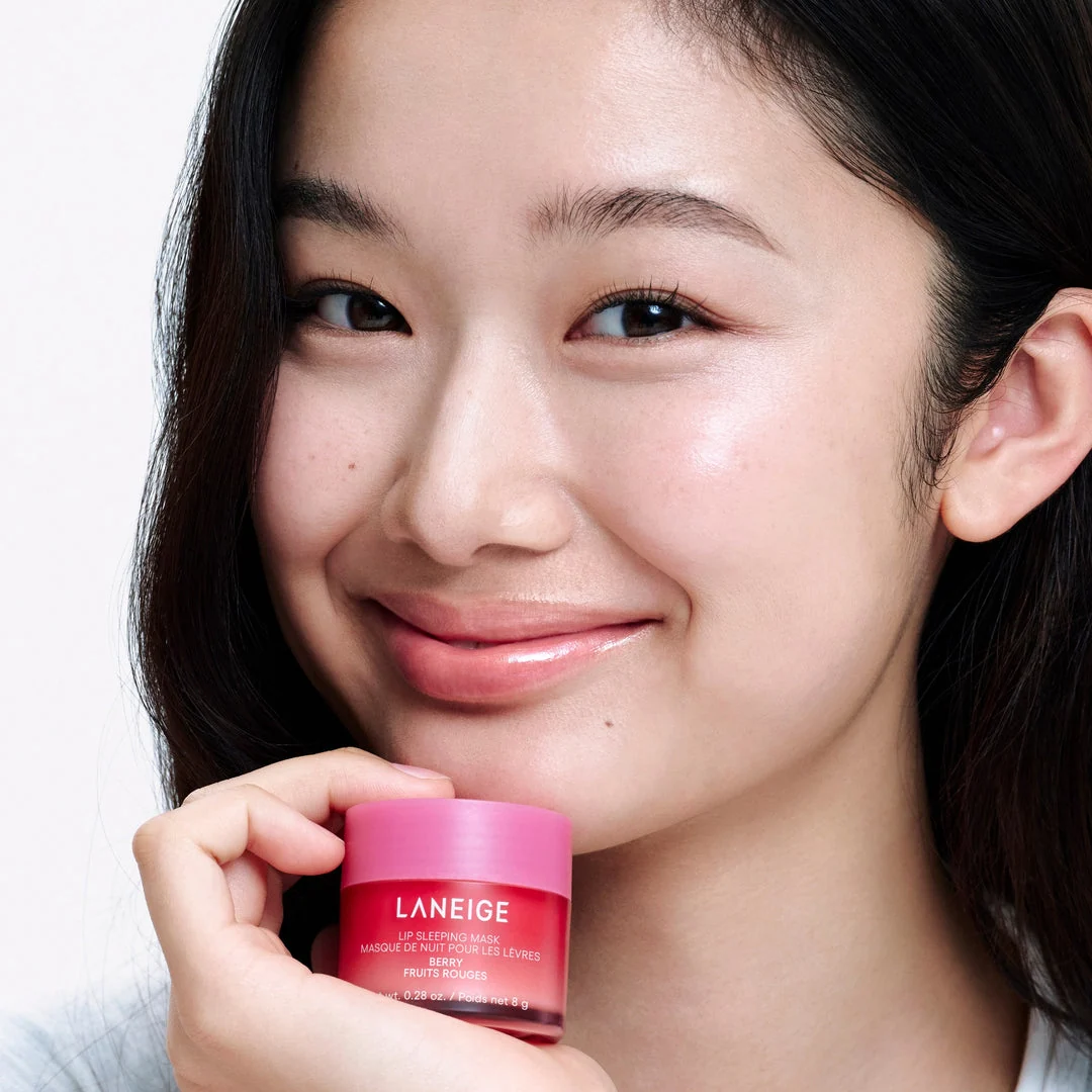 Model holding an 8g Berry mini jar with a glossy finish on her lips.