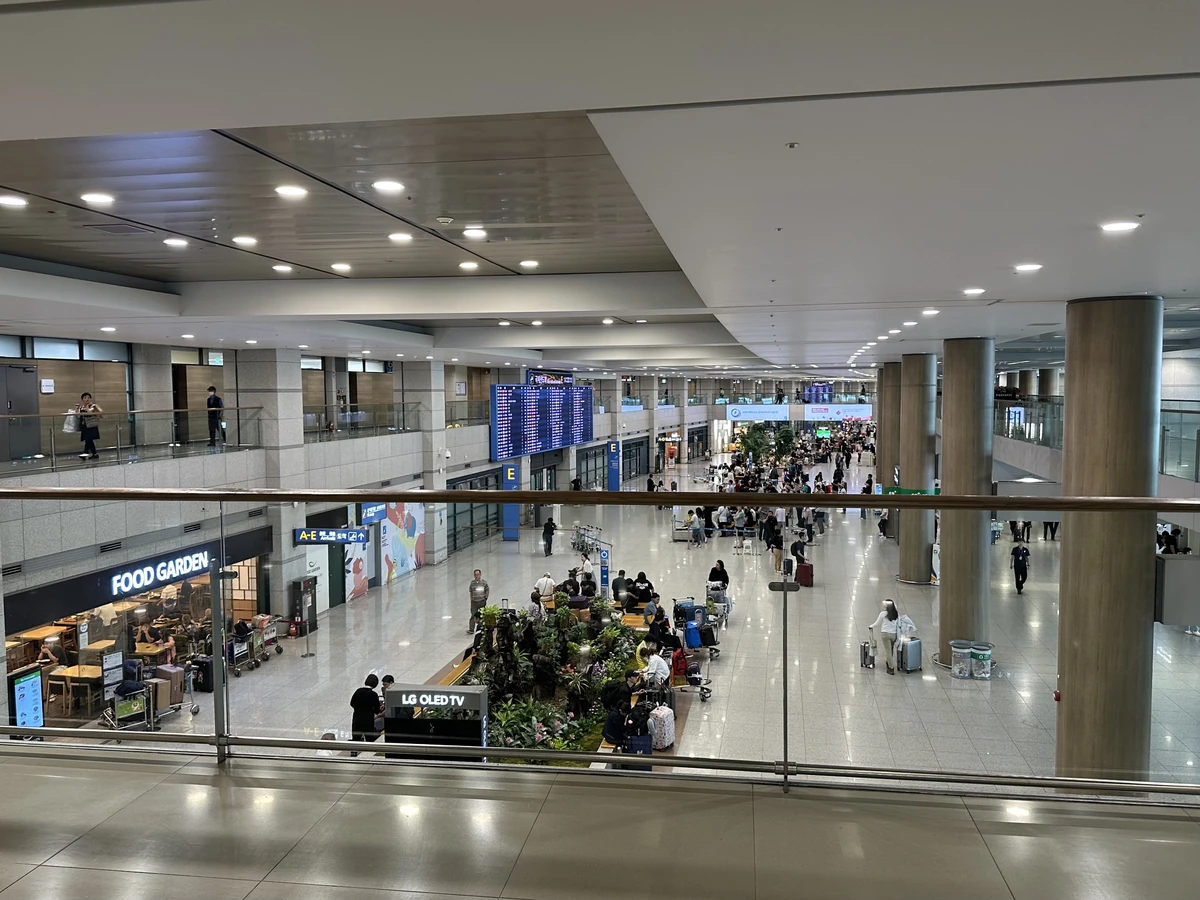 An elevated view of the Terminal 1 arrivals hall, with passengers and information displays