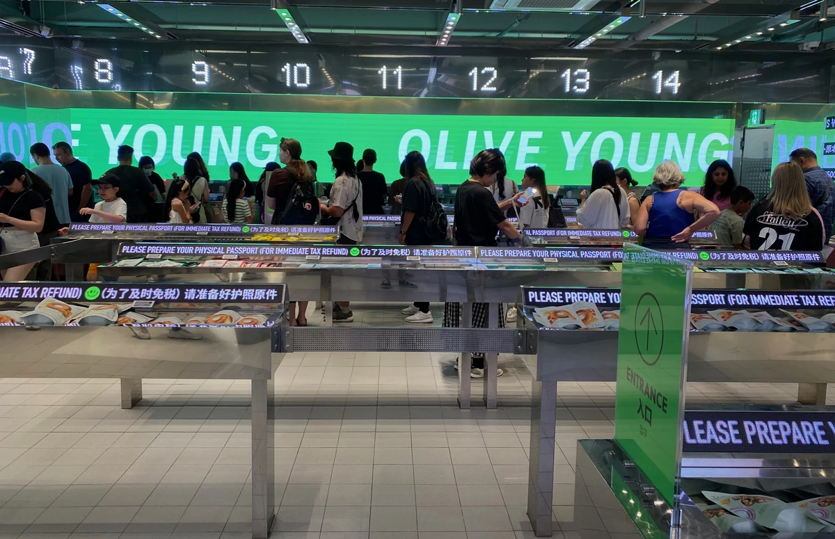 Numbered Olive Young checkouts with signs asking shoppers to prepare a physical passport for immediate tax refunds