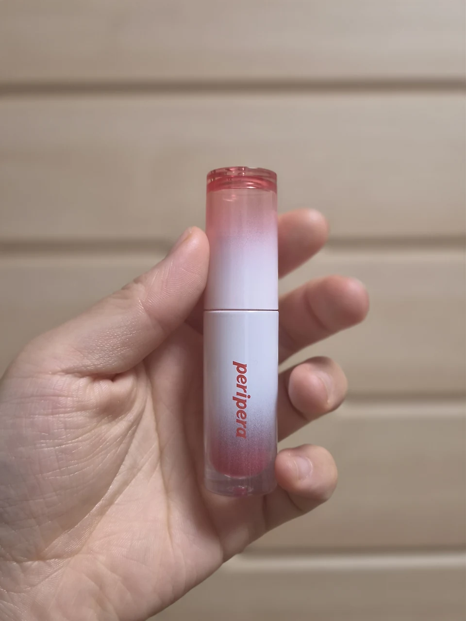 Hand holding the older Peripera Ink Mood Glowy Tint in shade 024, showing the full tube