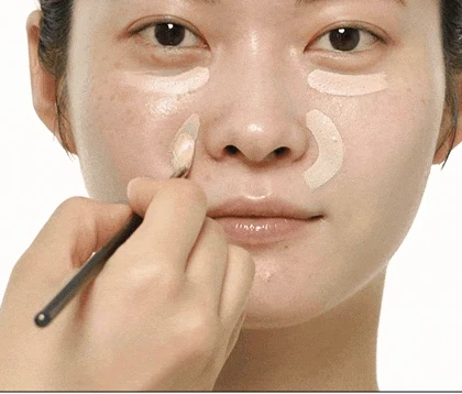A brush placing Triple Pot concealer beside the nose in the brand tutorial.